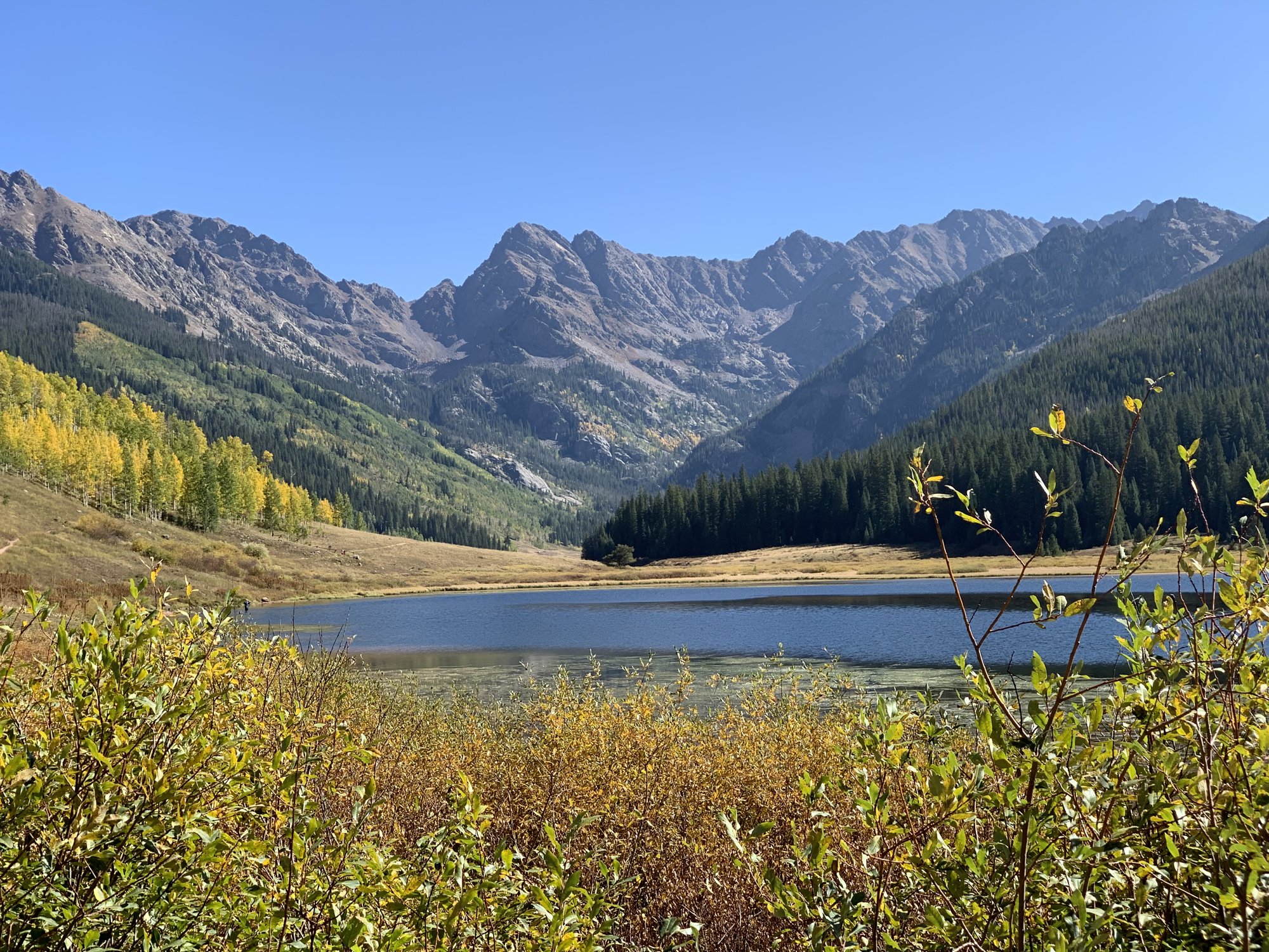 Piney Lake beneath the jagged peaks of the Gore Range, with golden aspens and autumn brush along the shore