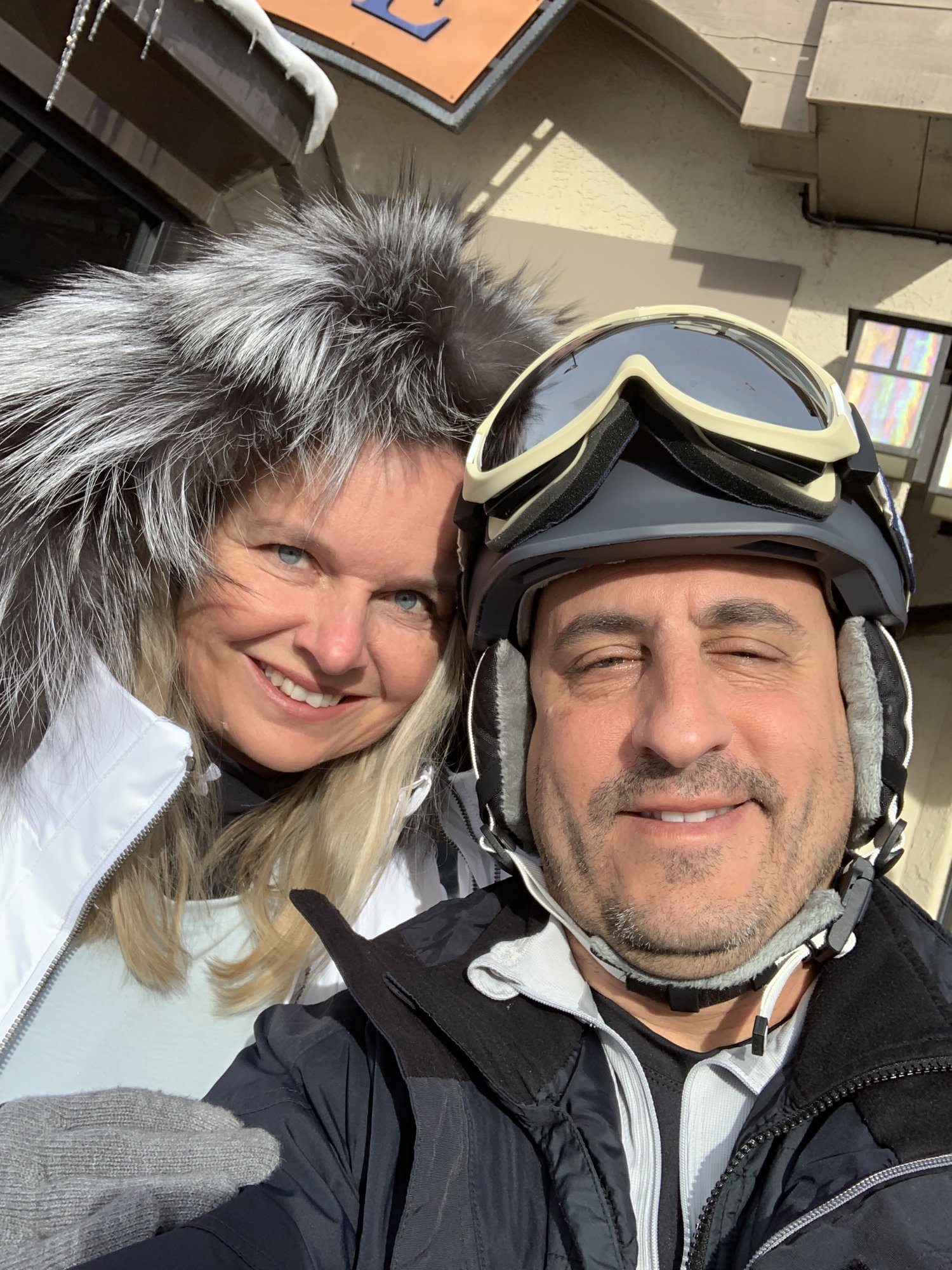 She-Stache in a fur-trimmed hood and He-Stache in a ski helmet and goggles taking a selfie in Beaver Creek