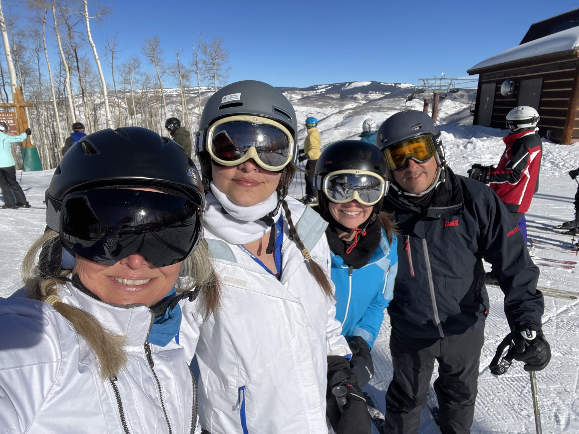 She-Stache, He-Stache and the Wee-Staches in helmets and goggles squeezed into a selfie on a sunny groomed slope at the top of Bachelor Gulch